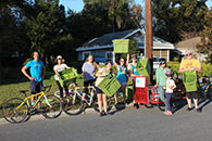 Group of people on a street corner holding green containers